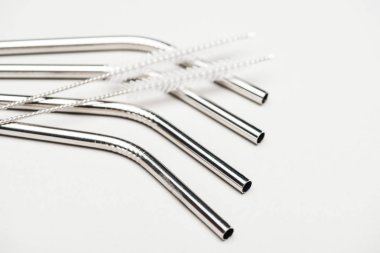 close up view of of stainless steel straws and cleaning brushes isolated on grey clipart
