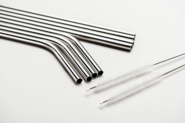 close up view of of stainless steel straws and cleaning brushes on grey clipart