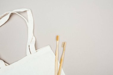 gri arka planda ahşap diş fırçaları ve Beyaz Pamuk çanta