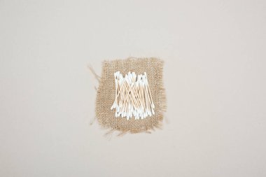 top view of cotton swabs on brown sackcloth on grey background clipart