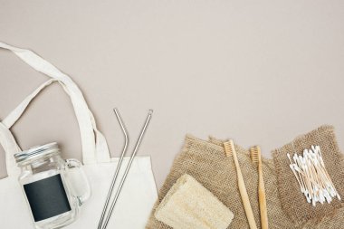 Bambu diş fırçaları, organik Loofah, pamuk SWABS, kahverengi çuvalı, kavanoz ile Pamuk çanta ve gri arka planda paslanmaz çelik pipetler