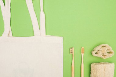 Açık yeşil arka planda organik bambu diş fırçaları, lif kabağı ve Pamuk çanta