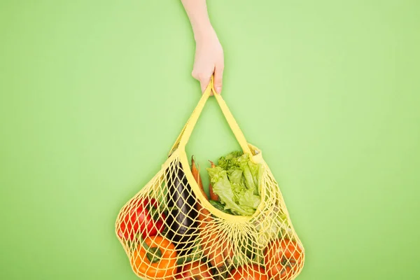 ライトグリーンに野菜全体で文字列バッグを保持している女性の部分的なビュー — ストック写真