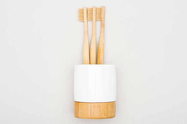 natural bamboo toothbrushes in stand on grey background