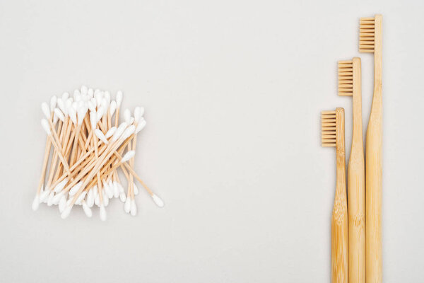 top view of bamboo toothbrushes and cotton swabs on grey background