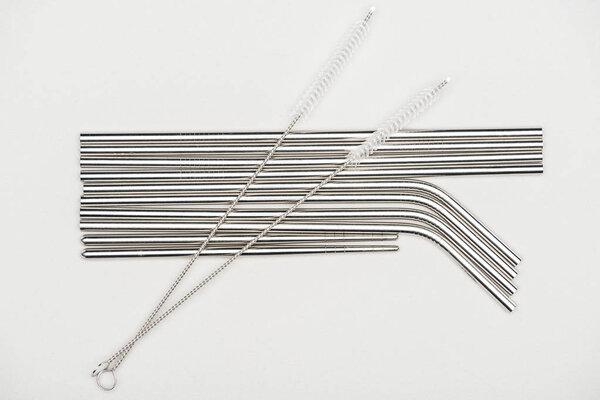 top view of stainless steel straws and cleaning brushes isolated on grey