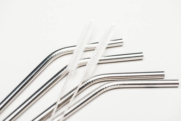stainless steel straws and cleaning brushes isolated on grey