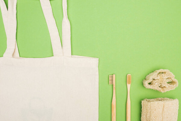 organic bamboo toothbrushes, loofah and cotton bag on light green background