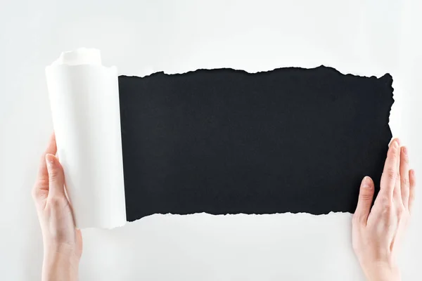 黒の背景に圧延エッジで白い紙を保持している女性のクロップビュー — ストック写真