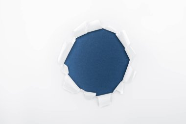 ragged hole in textured white paper on dark blue background  clipart