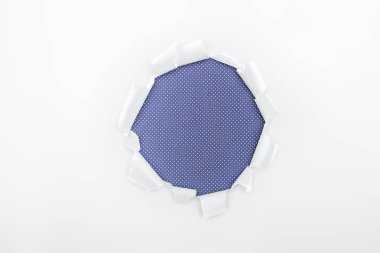 ripped hole in textured white paper on blue dotted background  clipart
