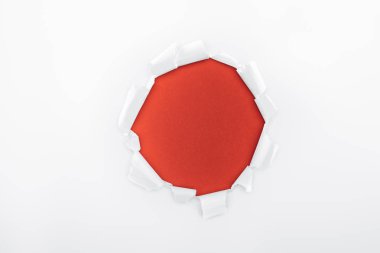ripped hole in textured white paper on red background  clipart