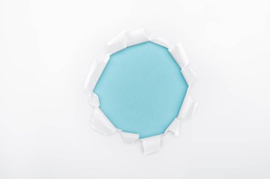 torn hole in textured white paper on blue background  clipart