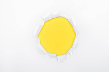 torn hole in white textured paper on yellow background  clipart