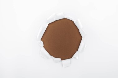 torn hole in white textured paper on brown background  clipart