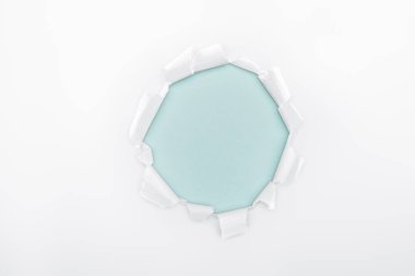 ripped  hole in white textured paper on light blue dotted background  clipart