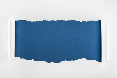 derin mavi arka planda kıvrılmış kenarları ile düzensiz dokulu beyaz kağıt 