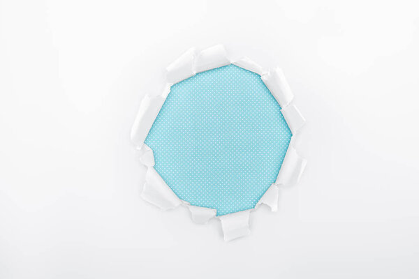 torn hole in textured white paper on light blue background 