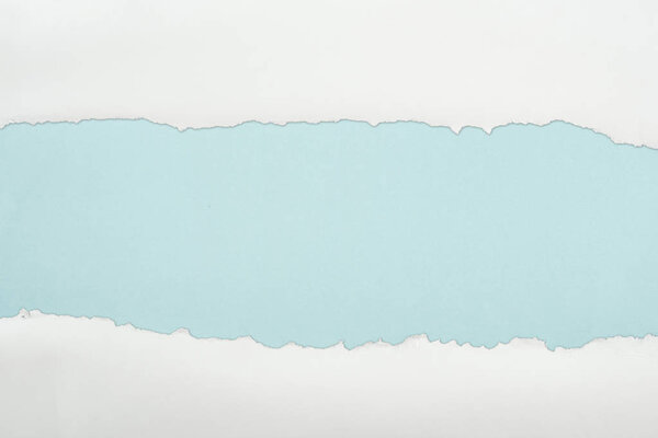ripped white textured paper with copy space on light blue background 