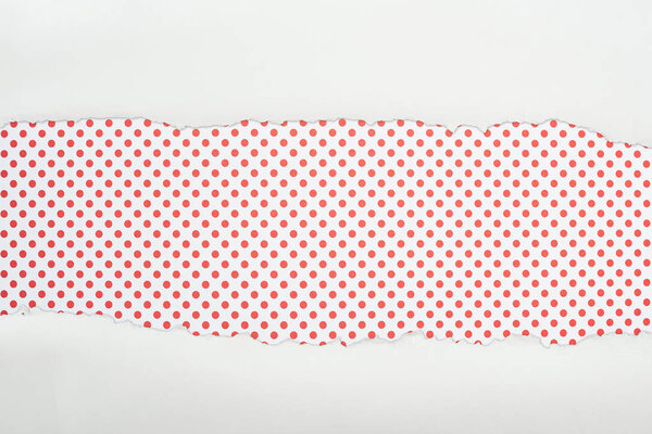 ripped white textured paper with copy space on red dotted background 