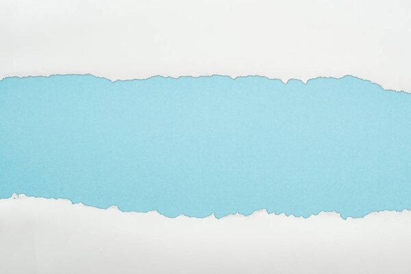 ragged white and textured paper with copy space on light blue background 