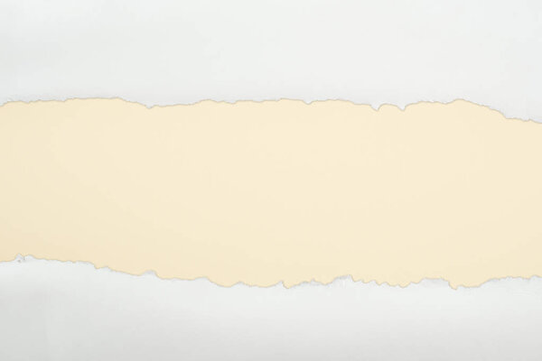 ragged white textured paper with copy space on beige background 