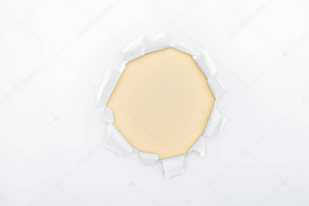 torn hole in white textured paper on ivory background 