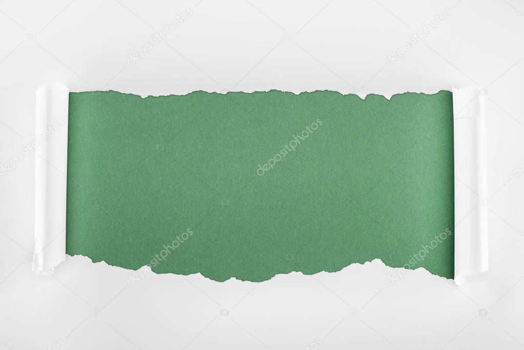 ragged textured white paper with curl edges on green background 