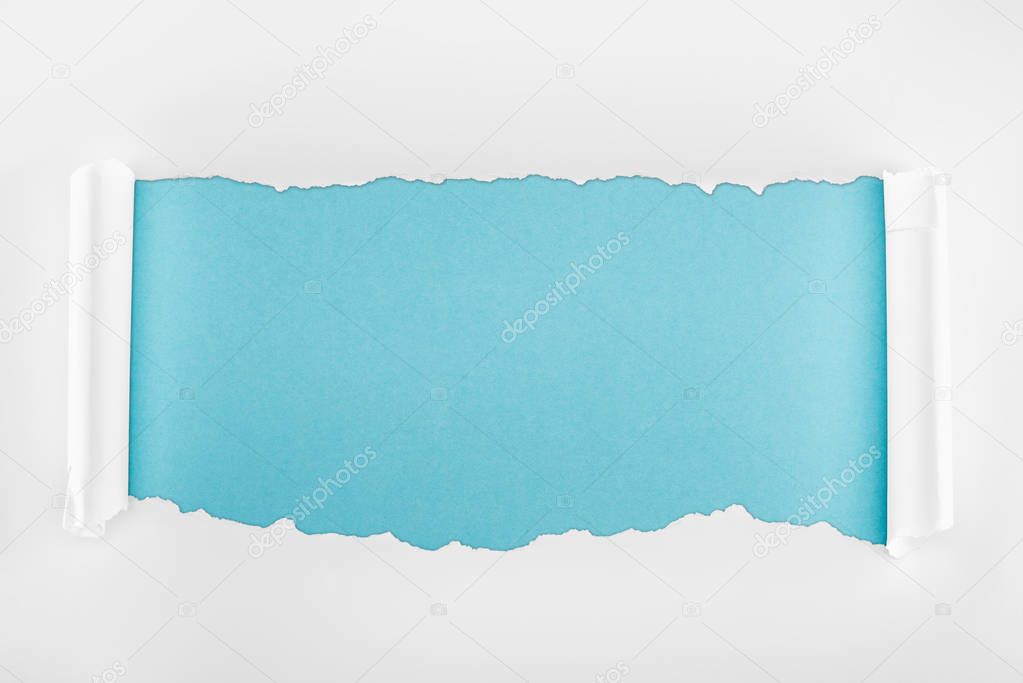 ripped white paper with curl edges on light blue background 