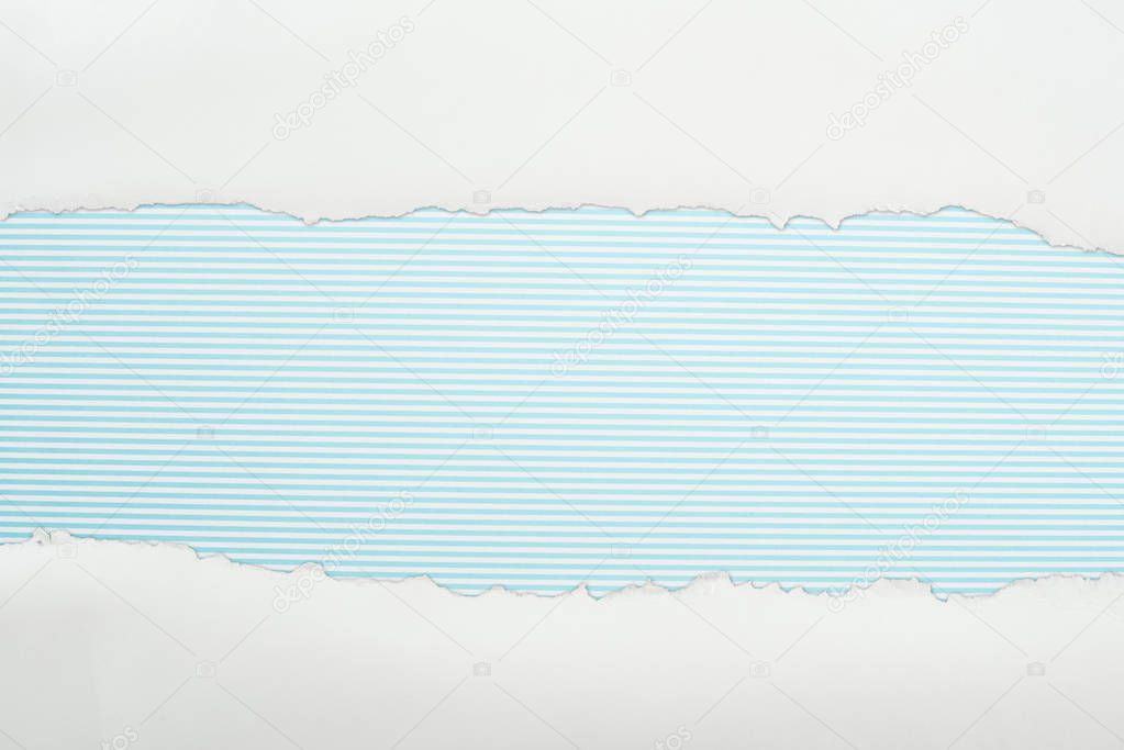 ragged white textured paper with copy space on light blue striped background 