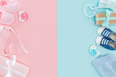 top view of pacifiers, gifts, hat, booties, sneakers, bonnets on pink and blue background clipart
