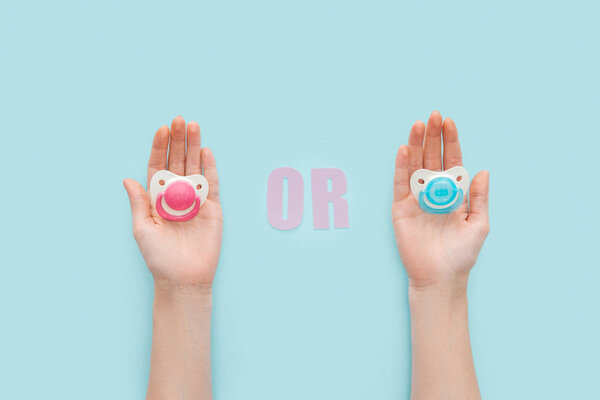 partial view of women holding pacifiers with or lettering 