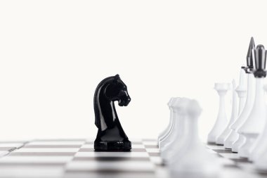 selective focus of chessboard with white chess figures and black knight isolated on white clipart