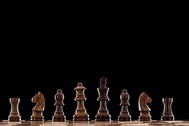 wooden chessboard with brown chess pieces isolated on black  clipart
