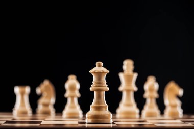 seçici odak üstünde siyah izole satranç tahtası üzerinde bej ahşap kraliçesi 