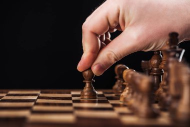 yapan erkek görünümünü kırpılmış siyah izole ahşap satranç tahtasında piyon ile hareket