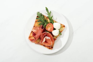 Top view of toast with cherry tomato, arugula and prosciutto on plate on white surface clipart