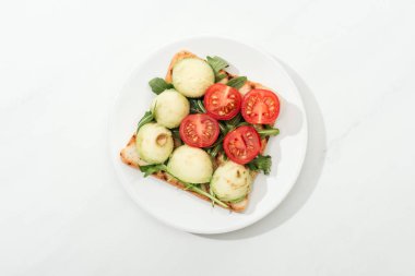 Tost domates ve roka ile üstten görünüm plaka beyaz yüzeyi üzerinde