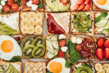 Top view of toasts with fried eggs, peanuts, cut vegetables and fruits  clipart