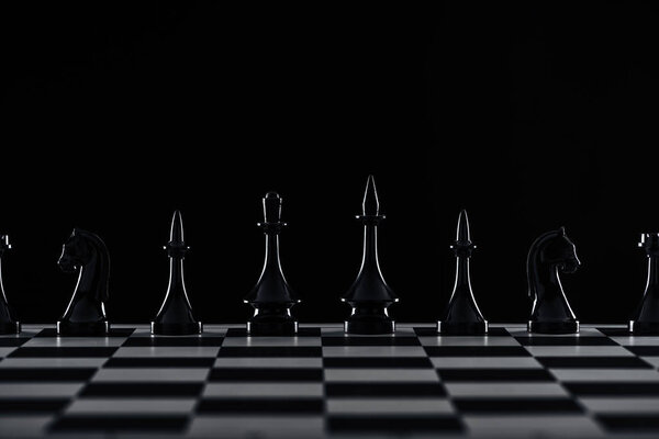 Шахматная доска с черными фигурами, изолированными на черном
