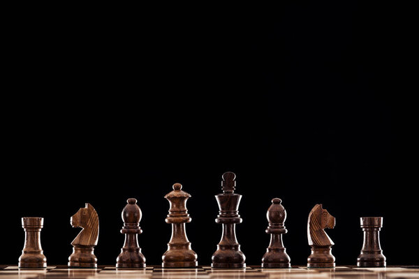 wooden chessboard with brown chess pieces isolated on black 