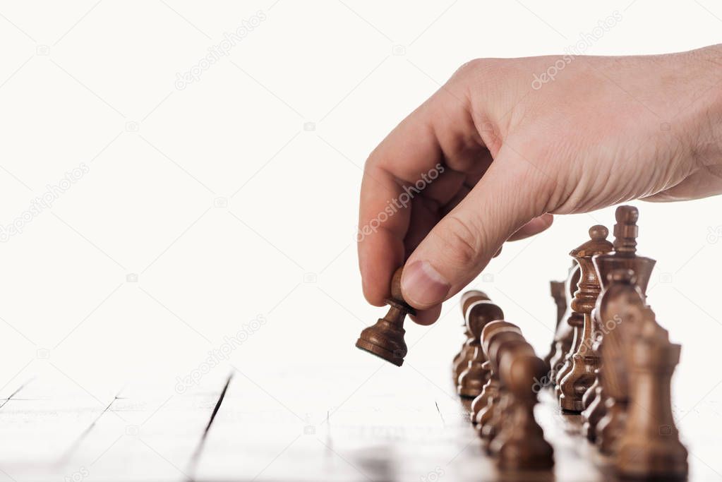 partial view of man doing move with brown pawn on wooden chessboard isolated on white