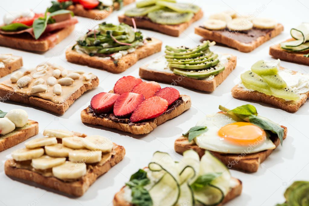 Toasts with cut fruits, fried egg and peanuts on white