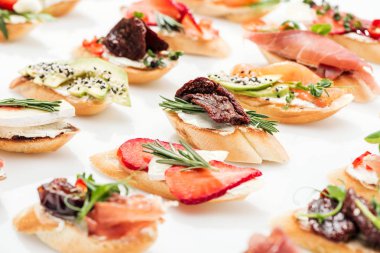 selective focus of italian bruschetta with dried tomatoes, prosciutto, avocado, strawberries and herbs clipart