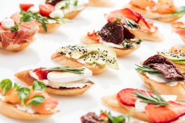 selective focus of italian bruschetta with dried tomatoes, avocado, brie cheese and herbs clipart
