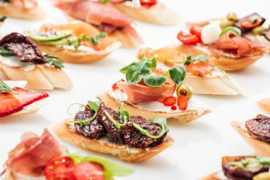 selective focus of italian bruschetta with dried tomatoes, prosciutto and herbs on white clipart