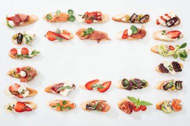 çerçevenin üstten görünüm ile prosciutto, somon, geleneksel İtalyan bruschetta meyve, sebze ve otlar beyaz üzerine yapılmış