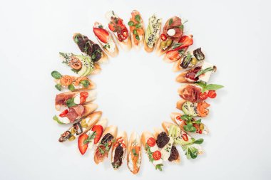 top view of round frame made of delicious italian bruschetta with salmon, prosciutto, herbs and various fruits with vegetables clipart