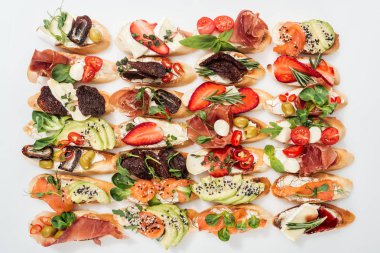 background of tasty italian bruschetta with salmon, prosciutto, dried tomatoes, avocado, strawberries and herbs on white clipart