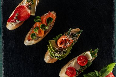 top view of italian bruschetta with salmon, tomatoes and avocado on wooden table clipart